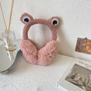Cute pink frog-shaped plush earmuffs for winter warmth in a cozy home setting.