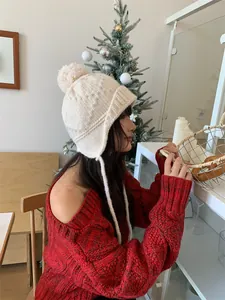 Vista lateral de mujer con gorro de punto blanco con orejeras y pompón en habitación acogedora
