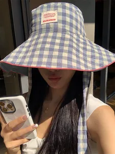 Close-up of a blue and white checkered wide-brim sun hat with a decorative patch.
