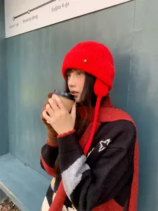 Asiatisches Model mit einer roten Strickmütze und Schal hält einen warmen Kaffeebecher