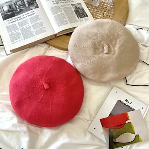 Top view of two breathable knitted beret hats in vibrant pink and soft beige colors