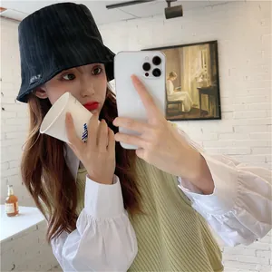 Close-up showing the pleated texture and label of a black bucket hat on a model