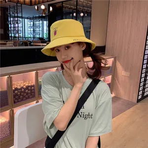 Close-up of yellow bucket hat with cute eggplant embroidery worn by a model