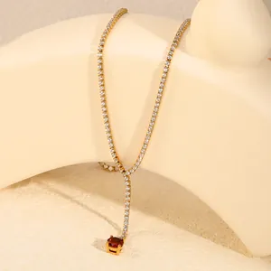 Gedetailleerde weergave van gouden tennis Y-ketting met een rode edelsteen hanger
