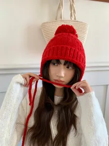 Gorro de punto rojo con orejeras y pompón llevado por una modelo en un ambiente invernal