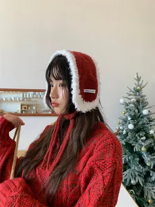 Close-up of red knitted plush earmuffs with white fluffy trim and adjustable neck ties