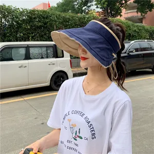 Vue latérale d'une femme portant un chapeau de soleil réversible en lin bleu et beige