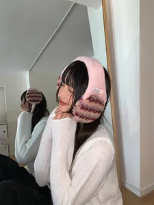 Cozy pink plush earmuffs with textured pattern on model wearing white sweater