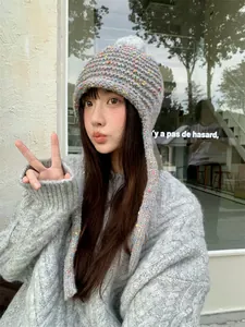 Asian model showcasing colorful candy-speckled knitted hat with cozy ear flaps for winter