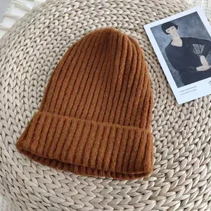 Close-up of warm brown knitted beanie hat with rib-knit texture on woven mat