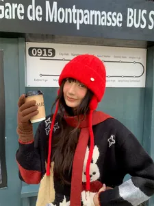 Nahaufnahme einer Frau mit einer roten Strickmütze mit Ohrenklappen für den Winter