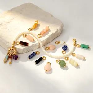 Gros plan de pendentifs en pierre naturelle irrégulière et breloques en acier doré