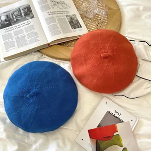Stylish knitted beret hats in vibrant orange and blue colors on a lifestyle background