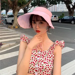 Jeune femme portant une visière en lin rose pour se protéger du soleil dans la rue.
