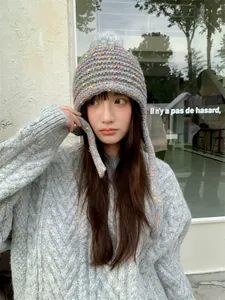 Detailed view of soft grey knitted beanie with colorful speckles and grey pom-pom