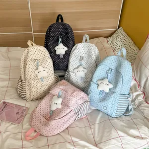 Group of five Korean style star pattern backpacks with cute plush star pendants on a bed