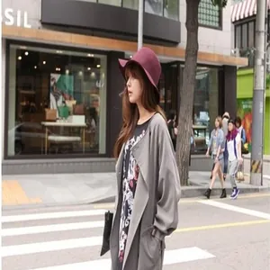 Side view of a woman wearing a stylish burgundy wool cloche hat in a street setting
