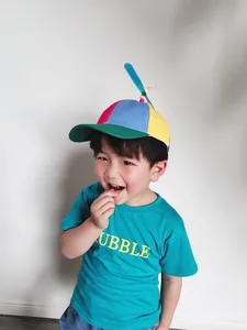 Close-up of a happy young boy wearing a vibrant multi-colored propeller sunshade hat