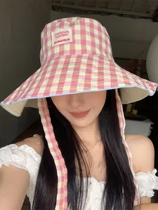 Stylish pink and cream checkered bucket hat with wide brim and chin strap