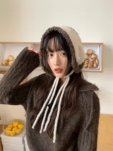 Close-up of a stylish Korean plush hooded earmuff hat with ties, modeled in a cafe
