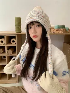 Cozy colorful mottled knit trapper hat with pom-pom worn by model in a soft studio setting
