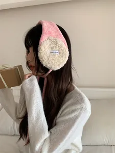 Gros plan sur des cache-oreilles en peluche rose et beige avec étiquette Haena Studio.