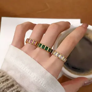 Detailed shot of gold-plated rings with colorful baguette-cut zircons on a model hand