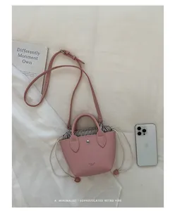 Vue détaillée d'un mini sac seau rose avec un sac à cordon rayé et un iPhone pour échelle.