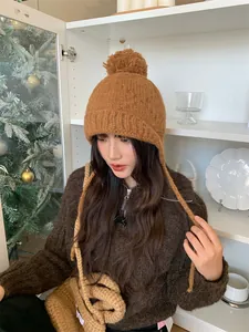 Modelo asiática con gorro de punto color caramelo con orejeras y pompón acogedor