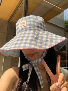 Close-up of a blue checkered wide-brim sun hat with adjustable tie straps.