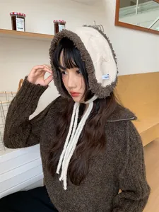 Cozy brown and white plush knit ear muffs with ties shown on a model in a warm room