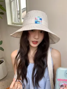 Modella asiatica con un elegante cappello alla pescatora beige e patch floreale