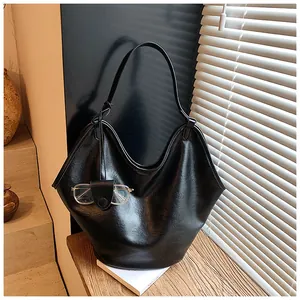 Detail shot of a large black hobo bag featuring soft leather and decorative glasses.