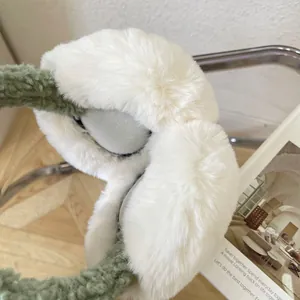 Macro close-up of soft plush earmuffs with white fur and green band for winter warmth