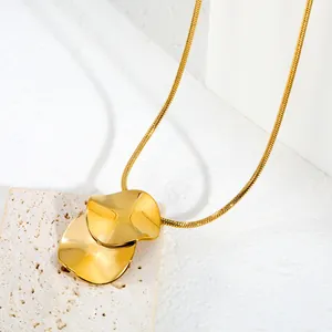 Gros plan d'un collier minimaliste en or avec pendentif à disque circulaire irrégulier