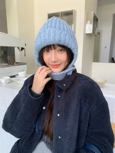Nahaufnahme einer blauen Strickmütze mit Ohrenklappen an einem Model im Café-Stil