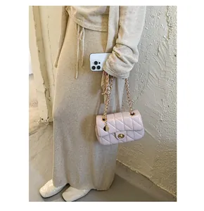 Close-up van een roze gewatteerde tas met gouden ketting en sluiting in trendy omgeving.