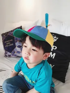 Child model wearing a colorful patchwork baseball cap with a spinning propeller detail