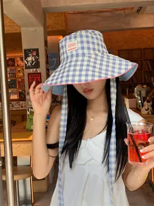 Asian model wearing a stylish blue checkered wide brim bucket hat with neck ties for sun protection