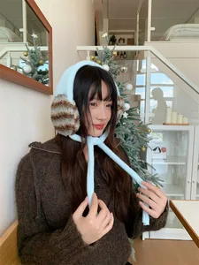 Asian model wearing cozy blue plush earmuffs with leopard print details in a cafe setting