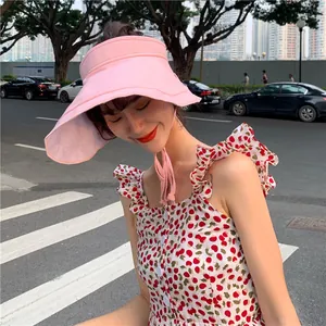 Jeune femme portant un chapeau pare-soleil rose élégant avec une robe à fleurs.