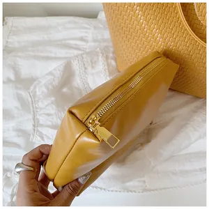 Detailed close-up of the smooth yellow leather pouch with a premium gold metal zipper.