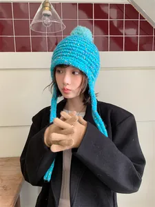 Cozy turquoise knitted trapper hat with colorful pom-pom and earflaps for winter