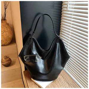 Close-up of black slouchy hobo bag with glasses holder on a textured wooden shelf