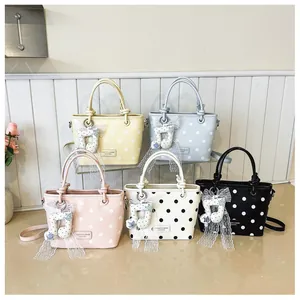 Detailed view showing five colorful polka dot handbags with lace music note charms
