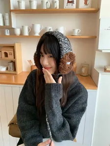 Jeune femme asiatique portant des cache-oreilles en peluche tricotés dans un café chaleureux.