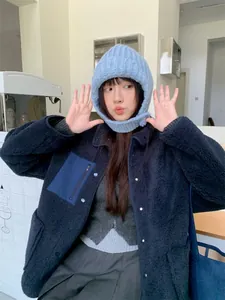 Model trägt eine hellblaue Strick-Balaclava-Mütze mit einer dunkelblauen Fleecejacke