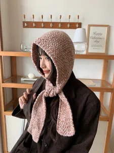 Cozy pink and white knitted hood scarf worn by a model in a warm interior setting