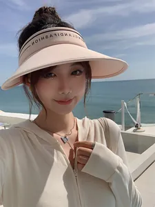 Mannequin asiatique portant une visière rose à large bord avec un fond de plage.