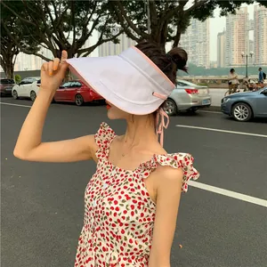 Mannequin asiatique portant une visière pare-soleil blanche avec bordure rose en extérieur